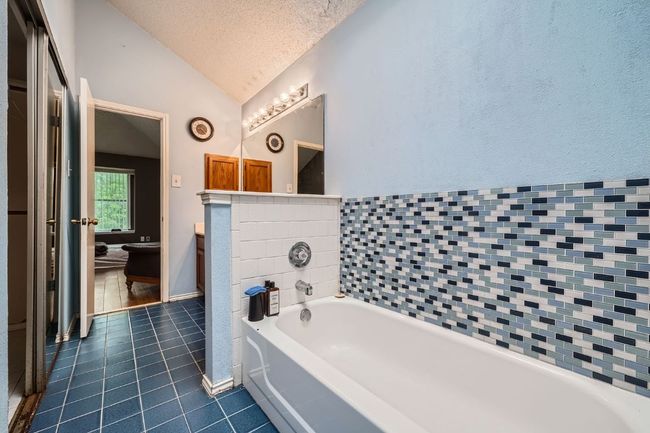 Full bathroom featuring vaulted ceiling, tile patterned floors, a textured ceiling, a garden tub, and vanity | Image 18