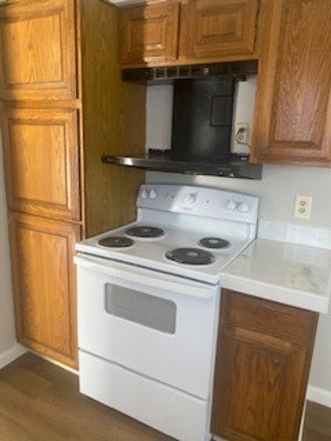 Kitchen with white range, brown cabinetry, dark wood-type flooring | Image 4