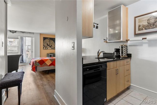 Kitchen featuring dark stone countertops, a sink, baseboards, light brown cabinetry, and dishwasher | Image 11