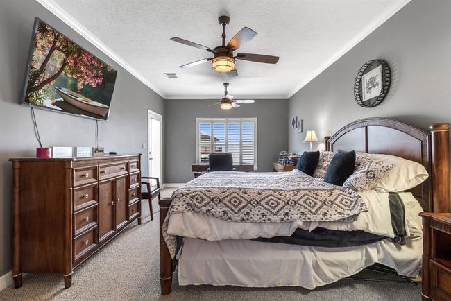 This spacious bedroom features a cozy decor with a large bed, wooden furniture, and a ceiling fan. The room is well-lit with natural light from a window and has a serene, modern ambiance. | Image 15