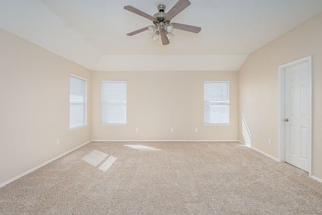 Carpeted empty room with lofted ceiling and a ceiling fan | Image 15