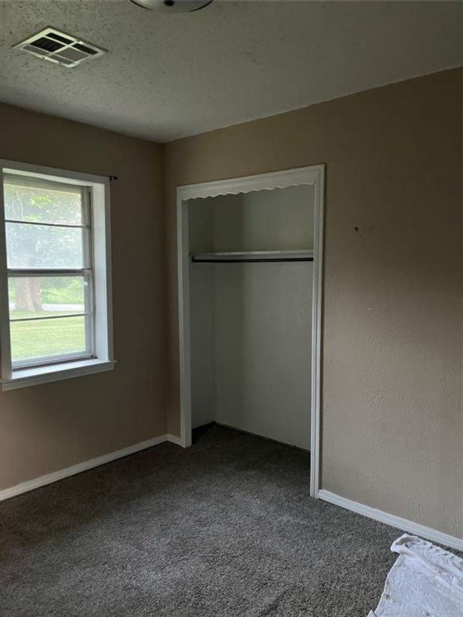 Unfurnished bedroom with dark carpet, a closet, and baseboards | Image 13
