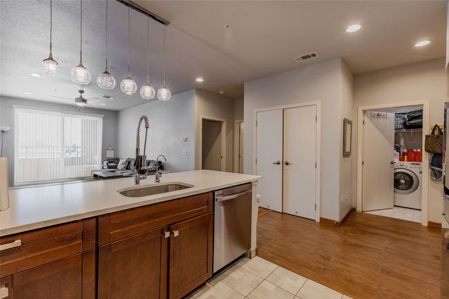 Kitchen featuring stainless steel dishwasher, washer / clothes dryer, light countertops, hanging light fixtures, and recessed lighting | Image 12