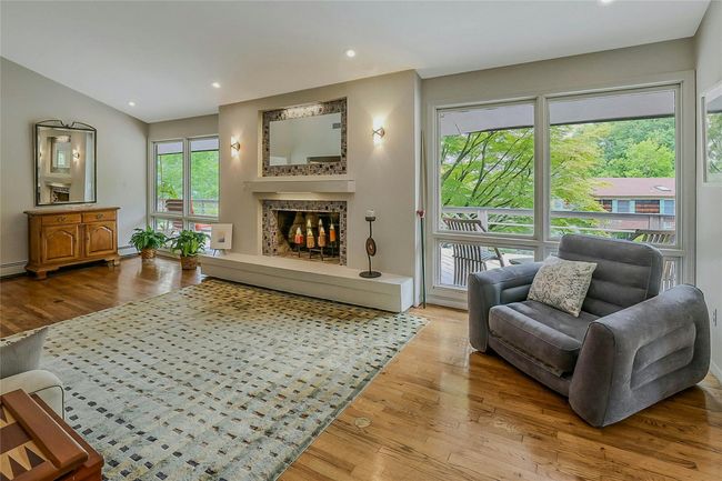 Living room featuring wood finished floors, a tiled fireplace, recessed lighting, and a baseboard radiator | Image 10