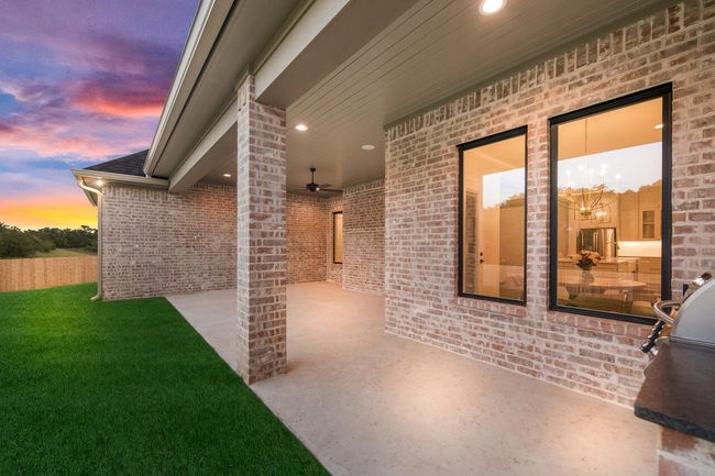 Patio terrace at dusk with ceiling fan, a patio area, a lawn, and area for grilling | Image 7