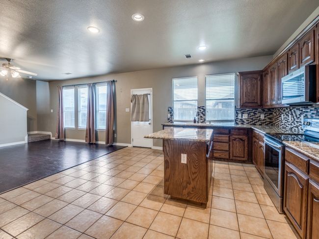 Kitchen featuring recessed lighting, a center island, backsplash, appliances with stainless steel finishes, and open floor plan | Image 6