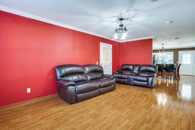 Living area with a chandelier, wood finished floors, and crown molding | Image 8