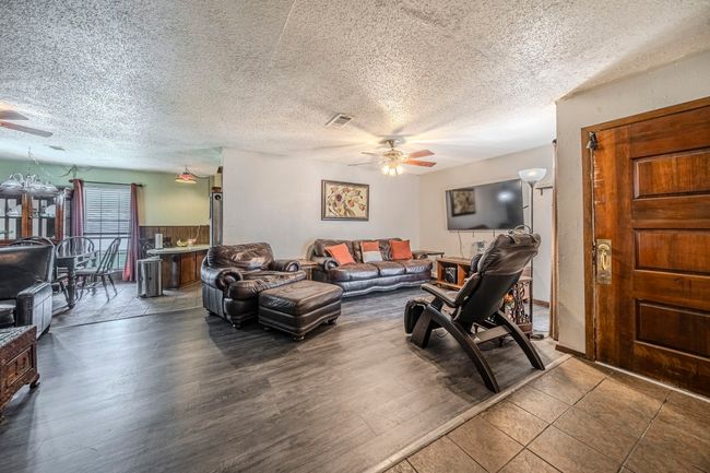 Living room featuring ceiling fan, a textured ceiling, and wood finished floors | Image 9