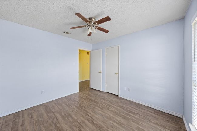 Empty room with a textured ceiling, a ceiling fan, and wood finished floors | Image 16