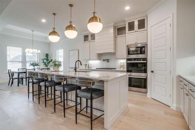 Kitchen featuring custom cabinetry to the ceiling, light hardwood floors, large island with Quartzite countertops, and beautiful hardware. | Image 3