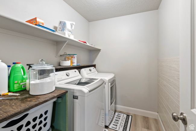 Washroom featuring light wood-style floors, a textured ceiling, washer and dryer, laundry area, and baseboards | Image 14