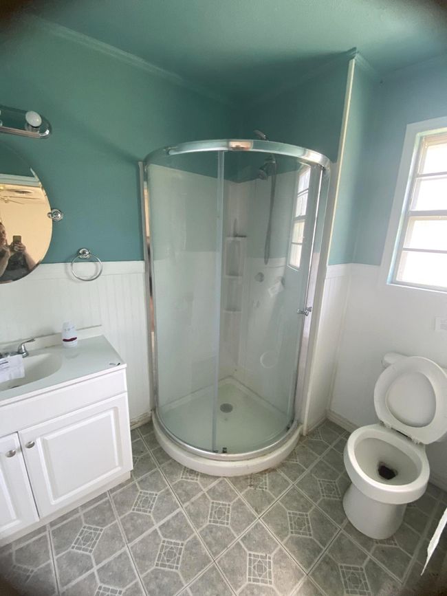 Full bathroom featuring a stall shower, tile patterned flooring, vanity, and a wainscoted wall | Image 7