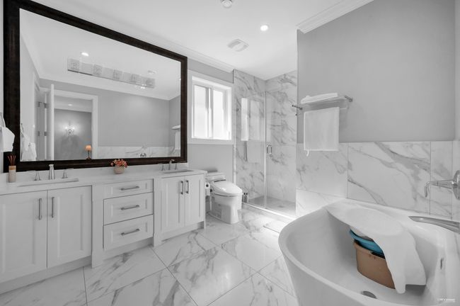 Full bathroom with crown molding, double vanity, a marble finish shower, a freestanding tub, and marble finish flooring | Image 30