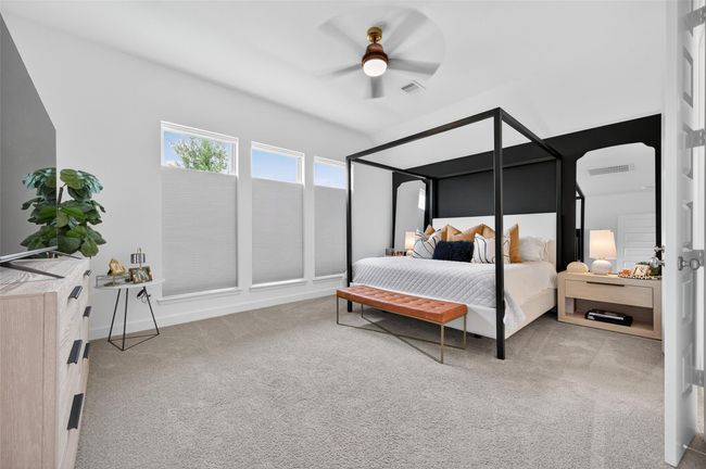 Spacious primary suite with tall ceilings, triple windows for natural light, and plush carpeting throughout. The open layout easily accommodates large furniture while maintaining a bright, airy feel. | Image 25
