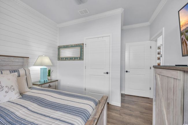 Bedroom with dark wood finished floors, crown molding, and wood walls | Image 24