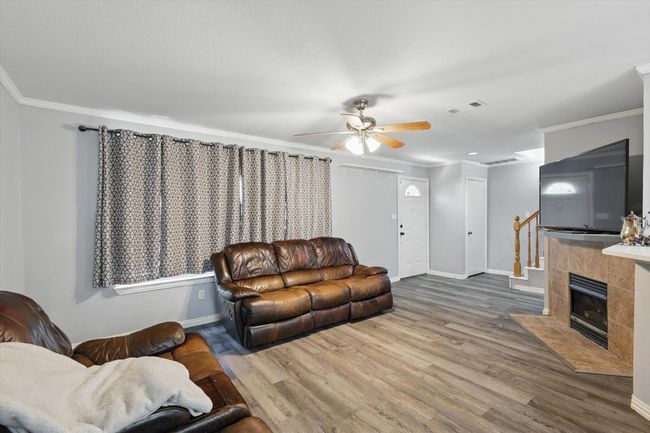 Living area with crown molding, wood finished floors, and a ceiling fan | Image 8