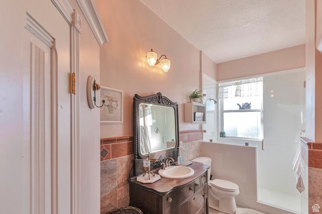 Bathroom with tile walls, toilet, vanity, and a textured ceiling | Image 25