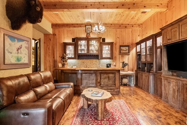 Bar area with pecky cypress ceiling, walls, wood floors, a chandelier, and decorative light fixtures | Image 19