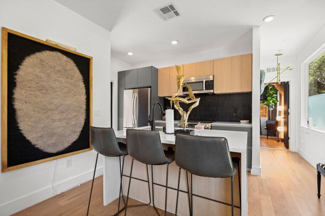 Kitchen featuring appliances with stainless steel finishes, light wood finished floors, decorative backsplash, light countertops, and recessed lighting | Image 10