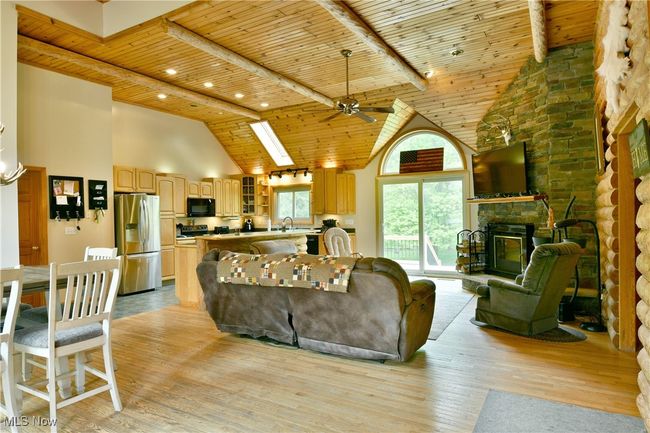 Living room with wood ceiling, high vaulted ceiling, light wood-style floors, a ceiling fan, and a stone fireplace | Image 7