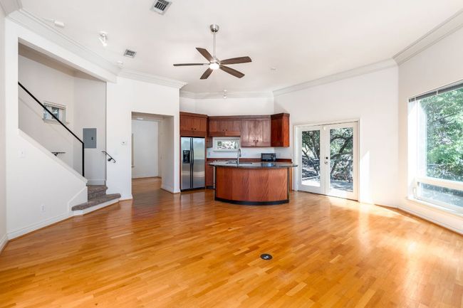 Kitchen with dark countertops, a sink, a ceiling fan, stainless steel refrigerator with ice dispenser, and visible vents | Image 7