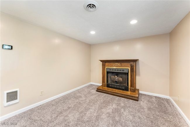 Unfurnished living room featuring a fireplace with raised hearth, carpet flooring, baseboards, and visible vents | Image 32