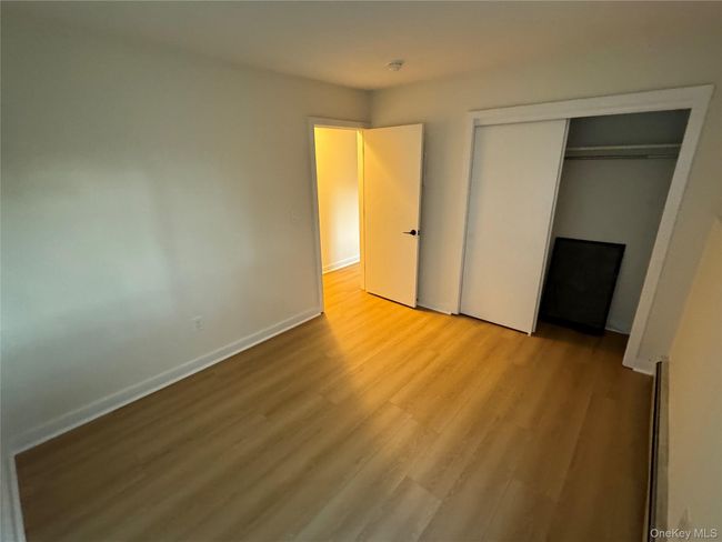 Unfurnished bedroom with wood finished floors, a baseboard radiator, and a closet | Image 10