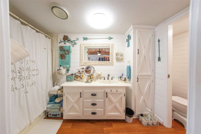 Bathroom featuring vanity, toilet, a textured ceiling, walk in shower, and wood-type flooring | Image 9