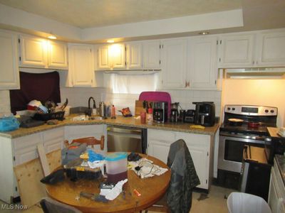 Kitchen featuring appliances with stainless steel finishes, white cabinetry, backsplash, and sink | Image 2