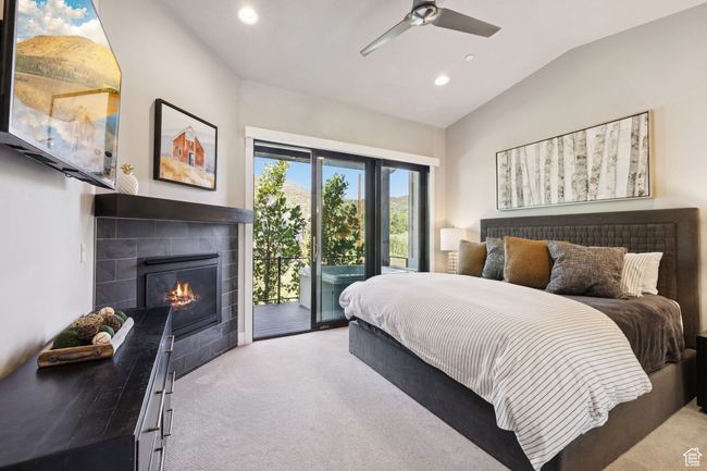 Bedroom with access to exterior, carpet flooring, vaulted ceiling, a tiled fireplace, and recessed lighting | Image 15
