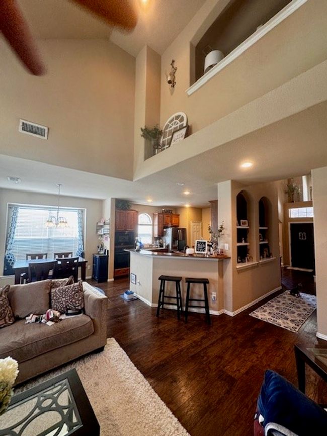 Living room featuring high vaulted ceiling, plenty of natural light, visible vents, and dark wood-style flooring | Image 9