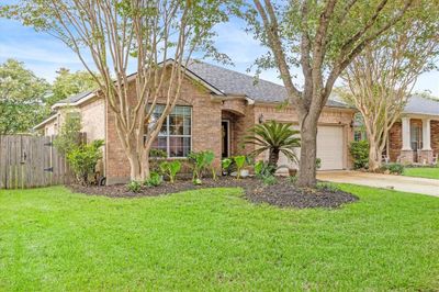 Be welcomed by exceptional curb appeal, featuring mature landscaping, towering trees, and a classic brick elevation. The charming covered entry and leaded glass door provide a beautiful first impression, setting the tone for this delightful home. | Image 2