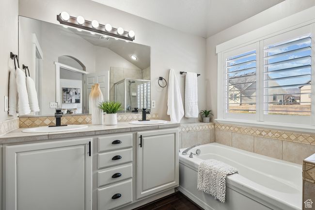 Bathroom featuring lofted ceiling, wood-type flooring, decorative backsplash, vanity, and plus walk in shower | Image 17