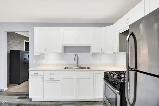 kitchen with stainless steel appliances, a sink, white cabinetry, and light wood-type flooring | Image 10