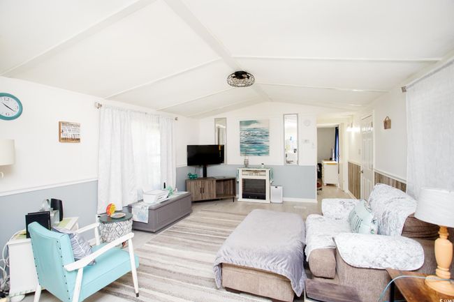 Living room with lofted ceiling, heating unit, and baseboards | Image 11