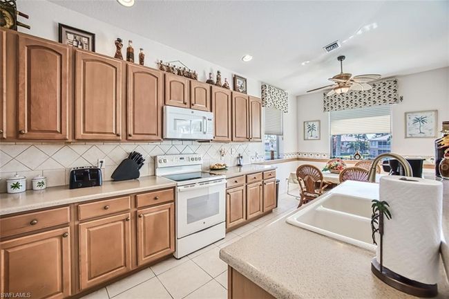 Kitchen with lofted ceiling, light stone counters, white appliances, and sink | Image 6