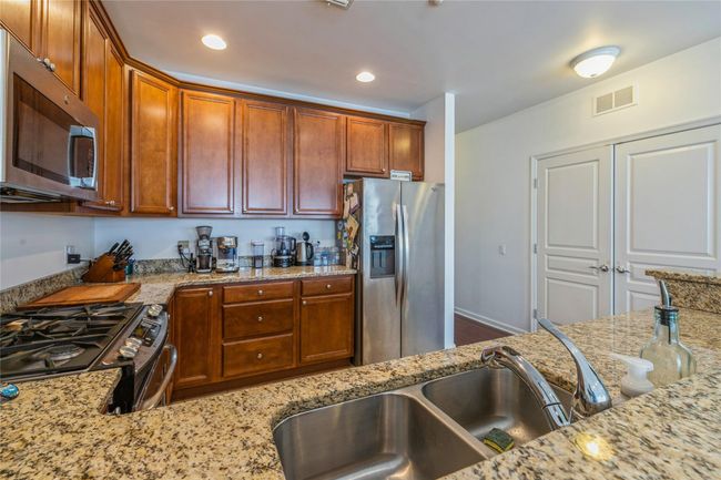 Kitchen with stainless steel appliances, visible vents, and light stone counters | Image 6