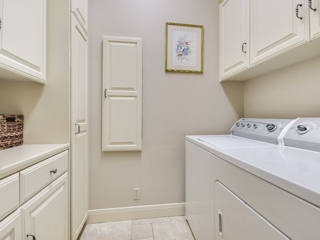 Laundry room with washer and clothes dryer, cabinet space, baseboards, and light tile patterned flooring | Image 14