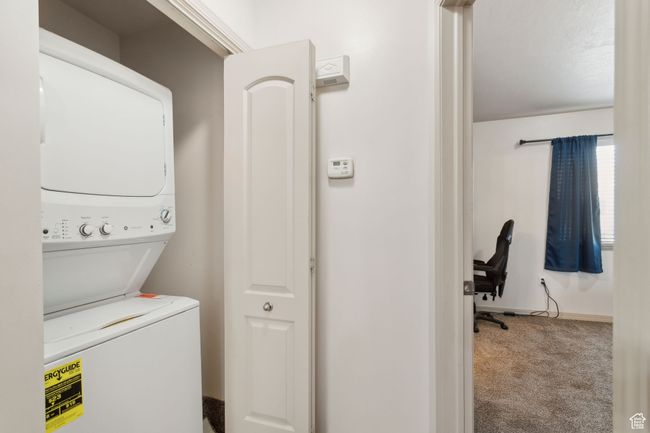 Washroom with stacked washer and clothes dryer, carpet floors, and baseboards | Image 17