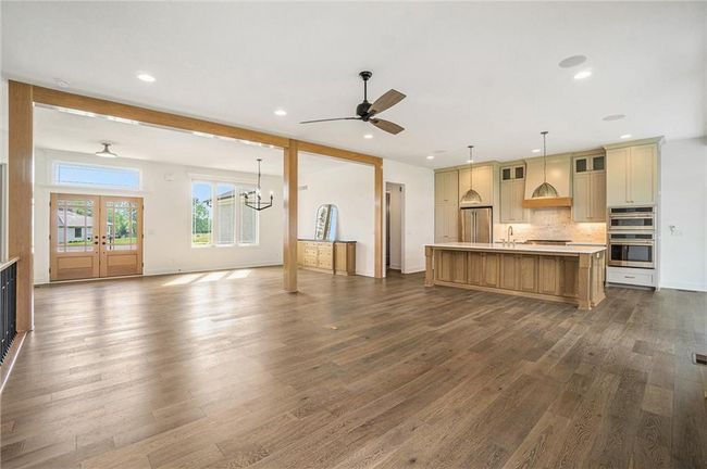 Unfurnished living room with dark wood finished floors, ceiling fan, a sink, a chandelier, and baseboards | Image 18