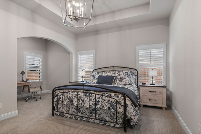 Carpeted bedroom featuring a chandelier, baseboards, a raised ceiling, and a towering ceiling | Image 15