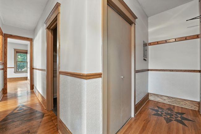 Spacious entry hall with hardwood floors, detailed wall trim, and a charming inlaid wood floor design. | Image 8