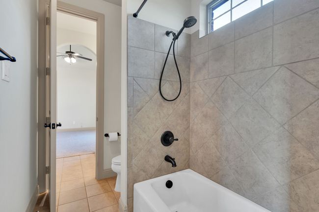 Bathroom with shower / bath combination, tile patterned floors, and ceiling fan | Image 19