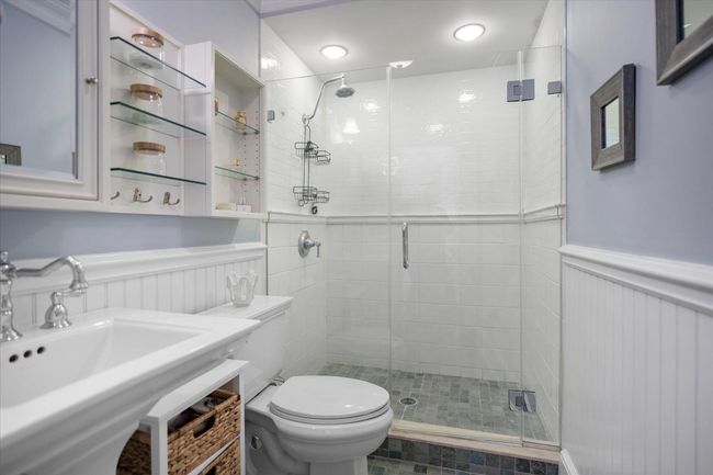 Bathroom featuring a sink, toilet, wainscoting, and a shower stall | Image 29