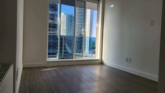 Empty room featuring plenty of natural light, dark wood-style flooring, and a city view | Image 15