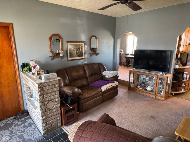 living area featuring arched walkways, ceiling fan, and a textured ceiling | Image 26