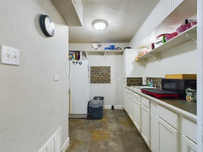 Kitchen featuring white cabinetry, open shelves, freestanding refrigerator, and stone finish flooring | Image 11