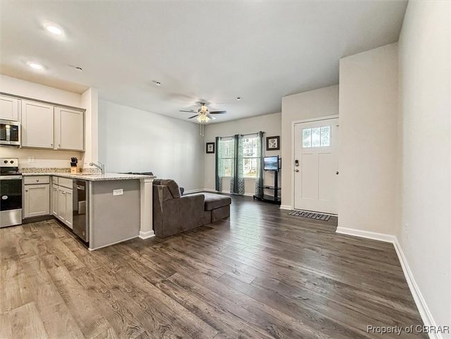 Kitchen featuring ceiling fan, appliances with stainless steel finishes, open floor plan, and dark wood-style flooring | Image 9
