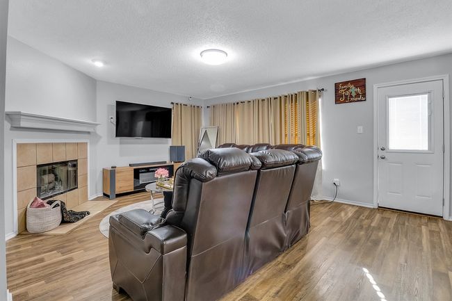 Living area featuring light wood-style flooring, a fireplace, baseboards, and a textured ceiling | Image 5