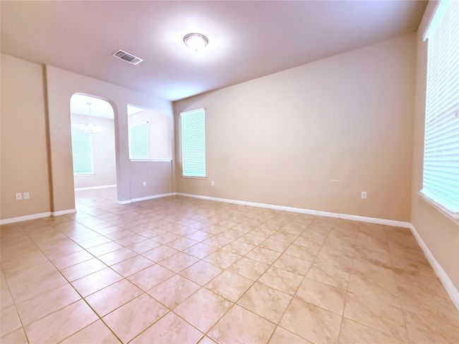 Unfurnished room with arched walkways, a chandelier, light tile patterned floors, and plenty of natural light | Image 4